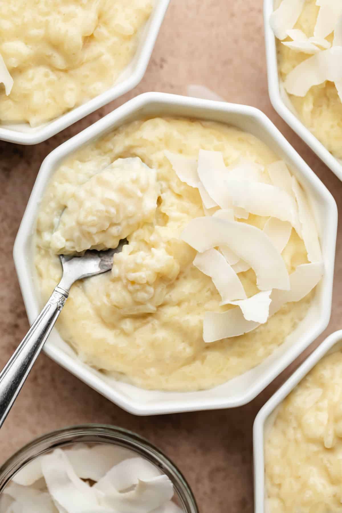 Un ramequin de pudding de riz au coco avec une cuillère tenant une portion de pudding.