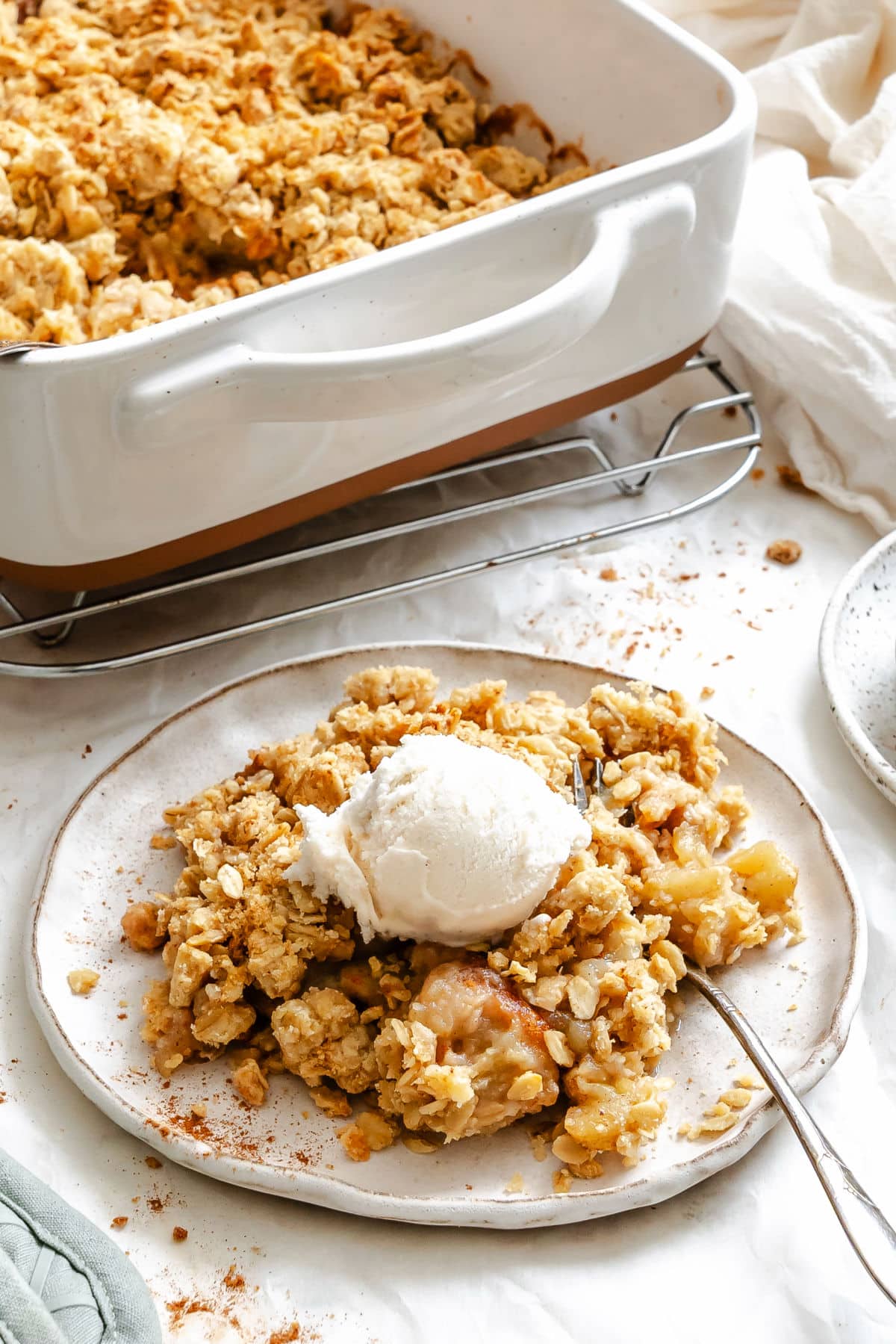 A plate of apple crisp topped with vanilla ice cream.