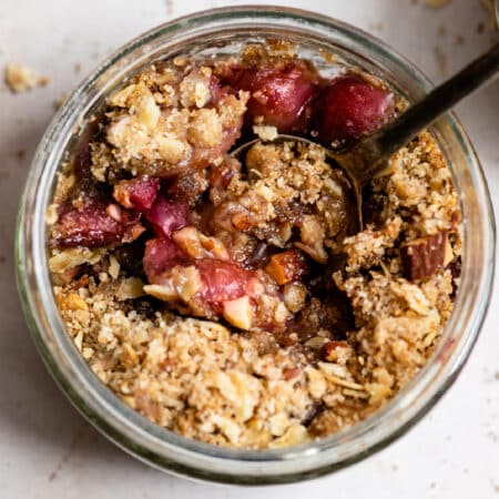 A ramekin on cherry crisp with a black spoon in it.