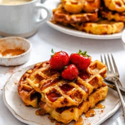 A plate of French toast waffles topped with fresh strawberries.