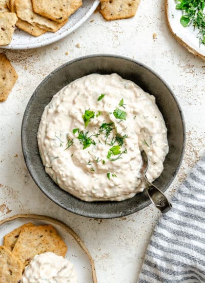 A dish of cottage cheese herb dip topped with fresh herbs.