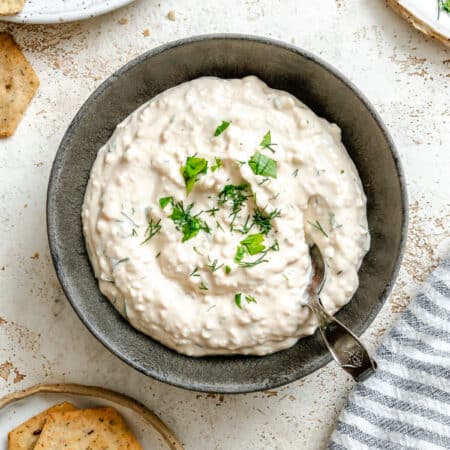 A dish of cottage cheese herb dip topped with fresh herbs.