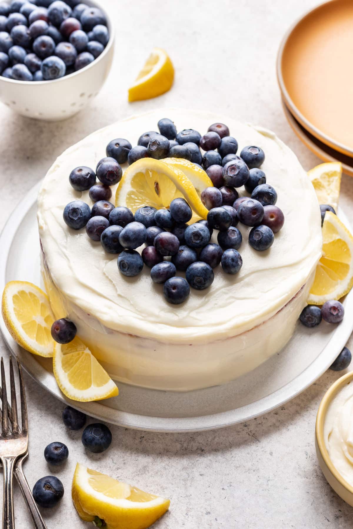 Lemon blueberry layer cake topped with fresh blueberries and lemon twists.