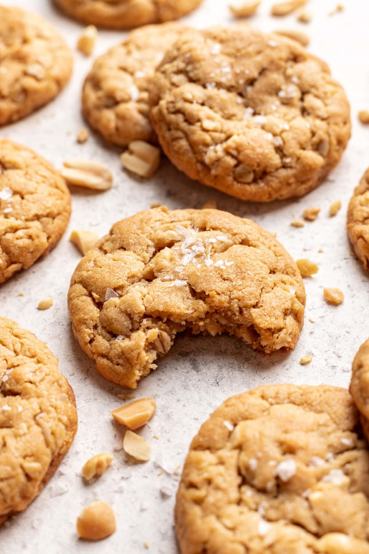 Peanut butter oatmeal cookie with a bite missing surrounded by overlapping cookies. 