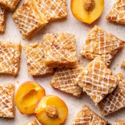 Peach crumb bars overlapping with fresh sliced peaches in between.