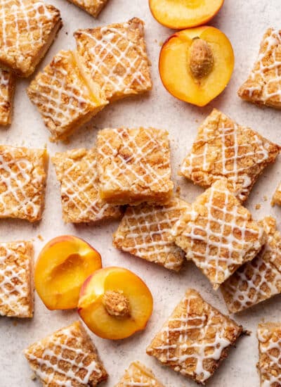 Peach crumb bars overlapping with fresh sliced peaches in between.