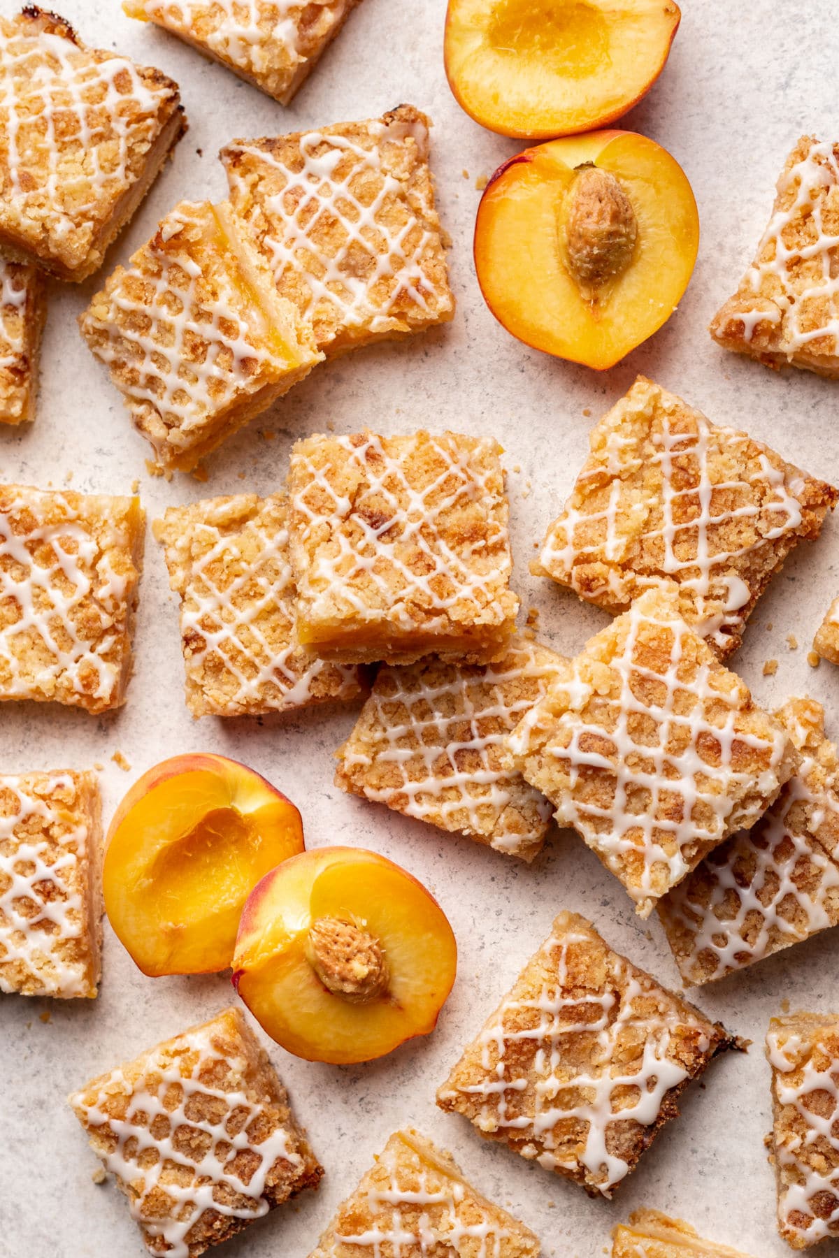 Peach crumb bars overlapping with fresh sliced peaches in between.