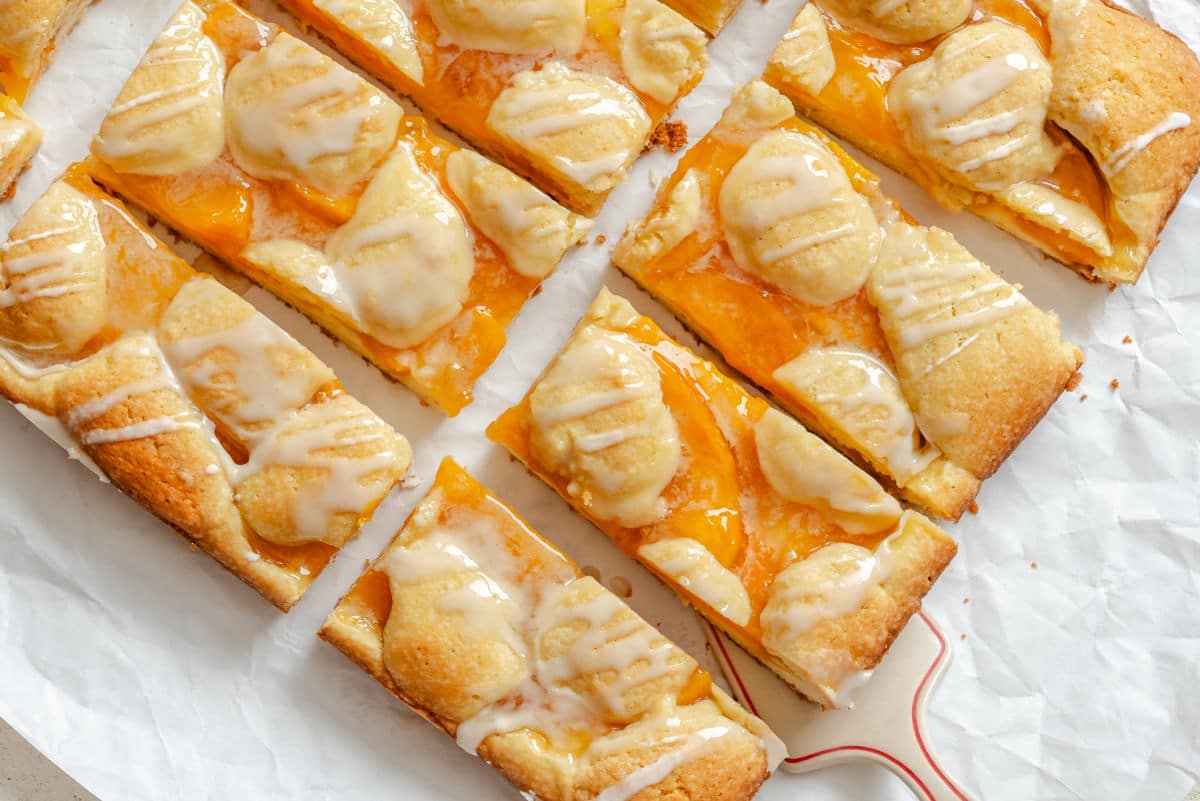Peach pie bars at an angle on a piece of white parchment paper.