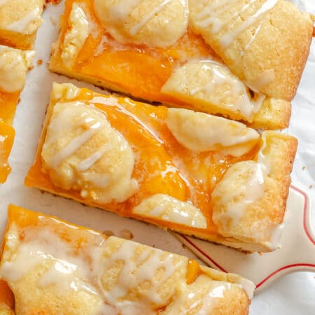 A server removing a peach pie bar from a row of bars.