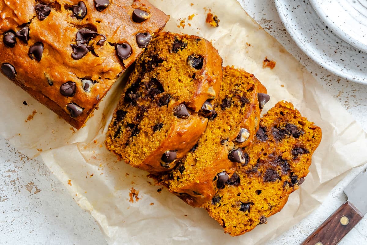 Slices of pumpkin chocolate chip bread on parchment paper.