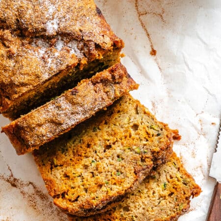 Three slices of whole wheat zucchini bread next to the rest of the loaf.