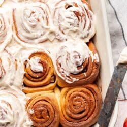 Partially frosted apple cinnamon rolls in a baking dish.