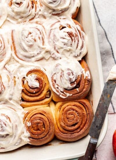 Partially frosted apple cinnamon rolls in a baking dish.