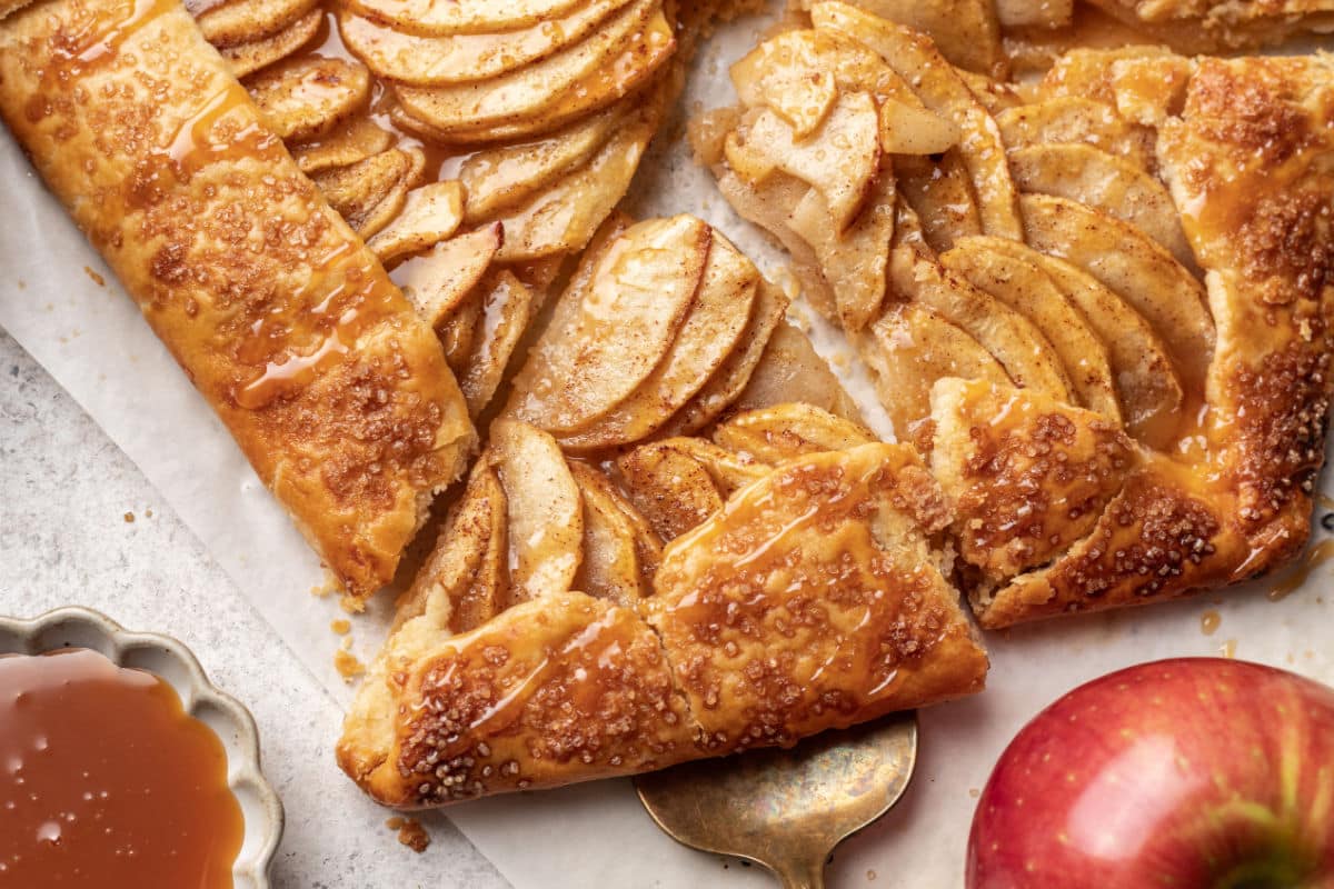 A cake server removing a slice from an apple galette.