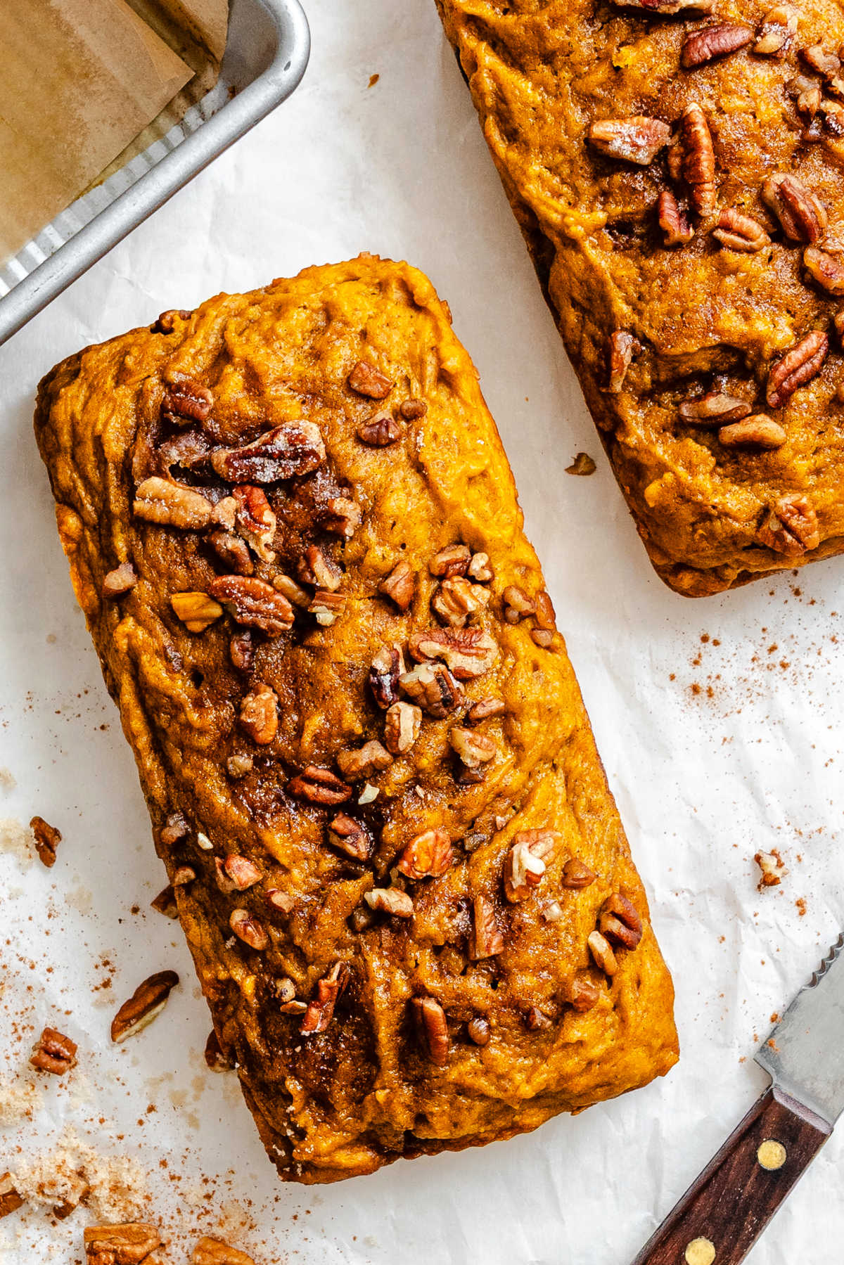 Two loaves of cinnamon sugar pumpkin bread on parchment paper.