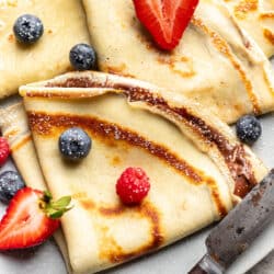 A plate of homemade crepes topped with fresh berries.
