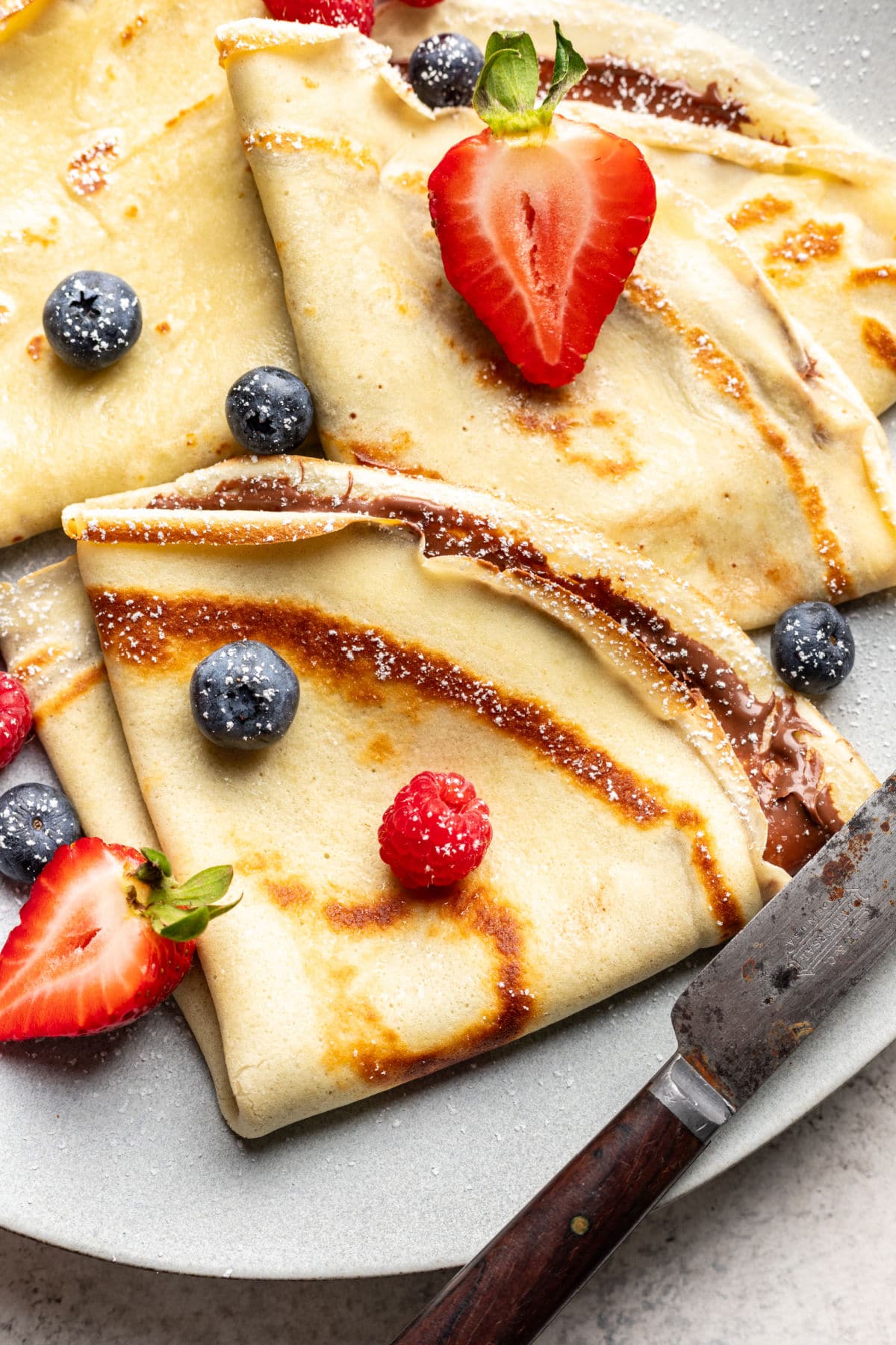 A plate of homemade crepes topped with fresh berries.