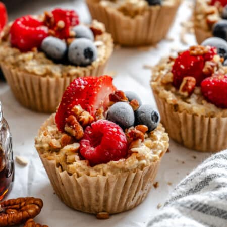 Freezer oatmeal cups next to a dish of maple syrup.