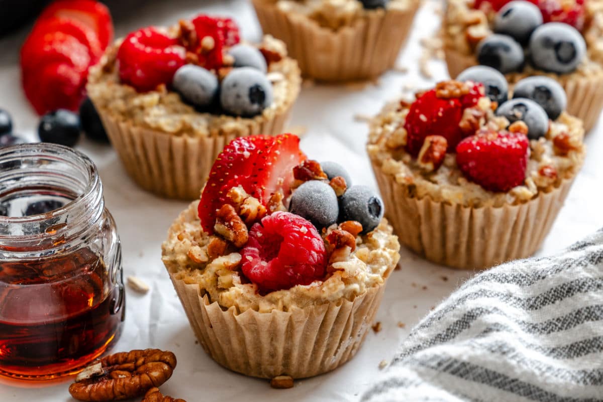 Freezer oatmeal cups next to a dish of maple syrup. 