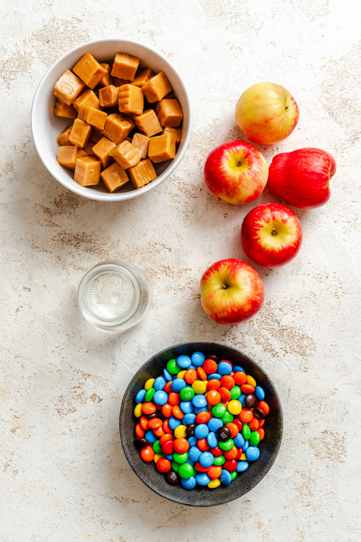 Ingredients for M&M caramel apples in dishes.