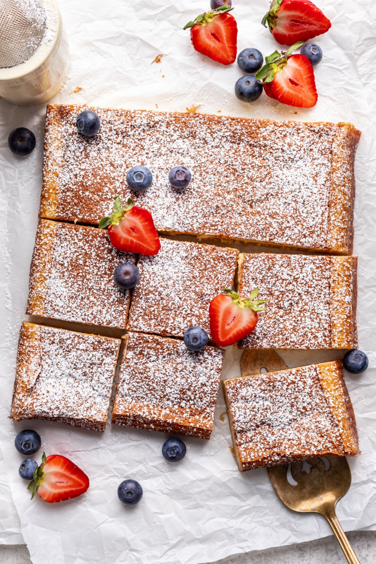 A baked magic cake topped with powdered sugar and fresh berries. 