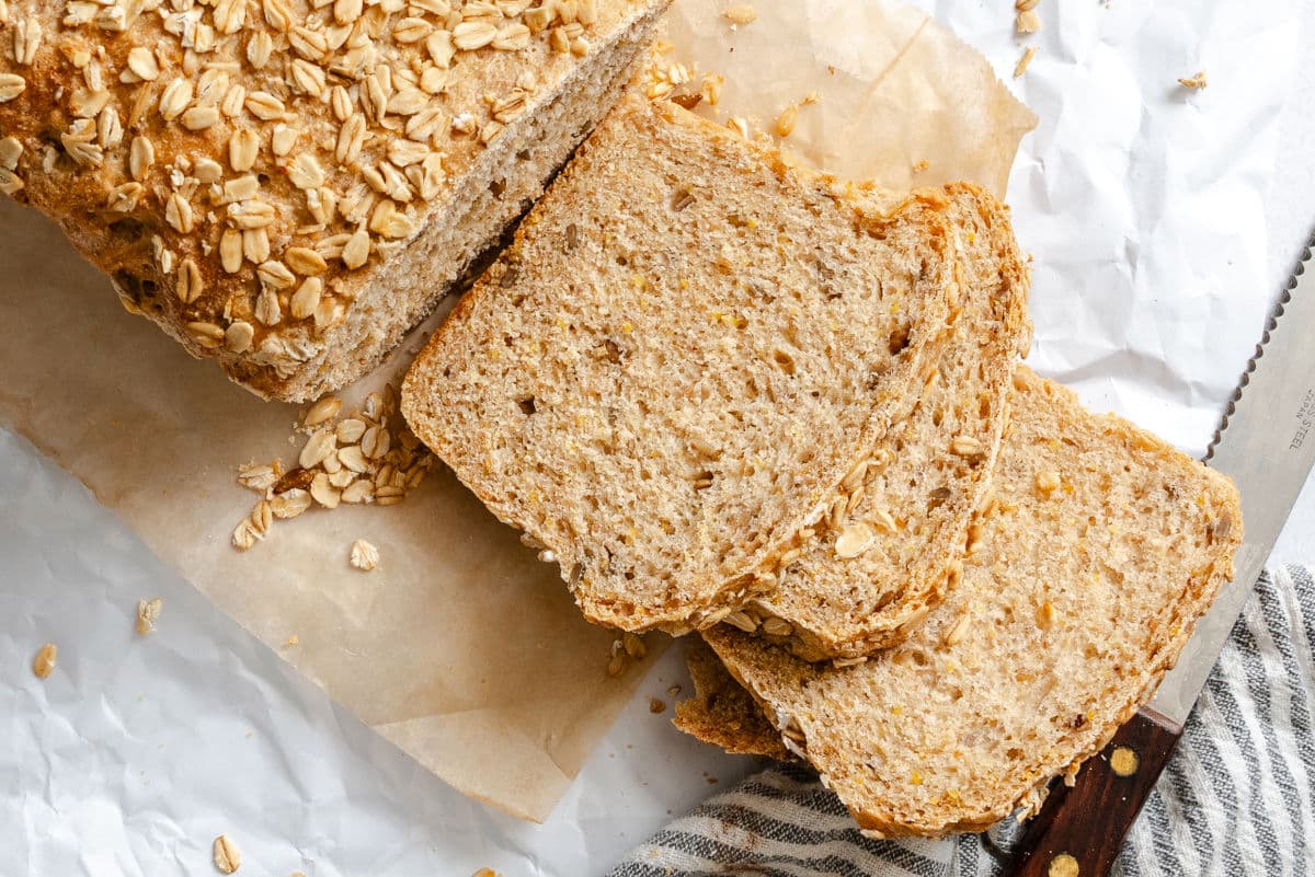 Multigrain Bread Recipe Three slices of multigrain bread on white parchment paper.