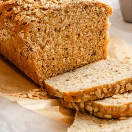 A loaf of multigrain bread with three slices cut next to it.