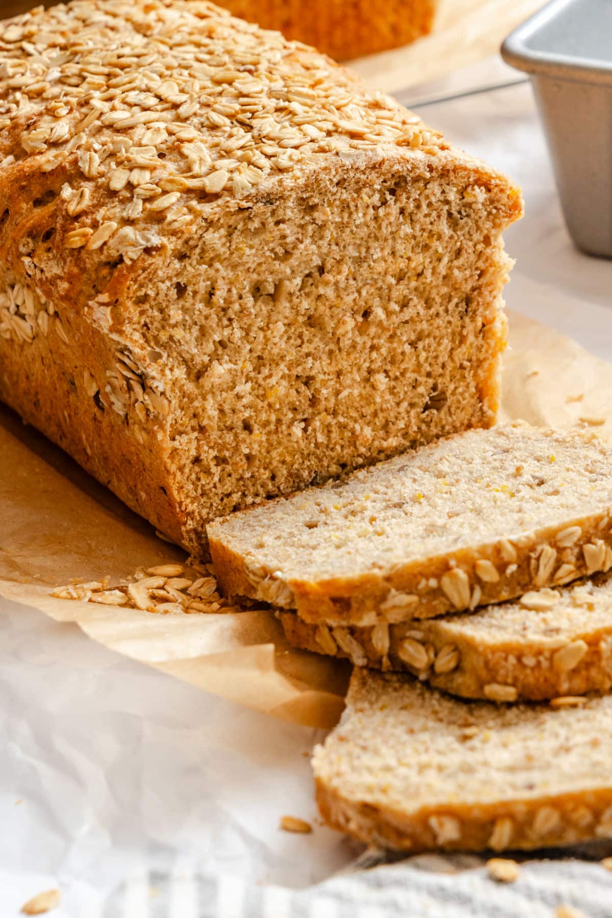 Multigrain Bread Recipe A loaf of multigrain bread with three slices cut next to it.