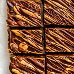 Cut no bake cookie bars in a row on white parchment paper.