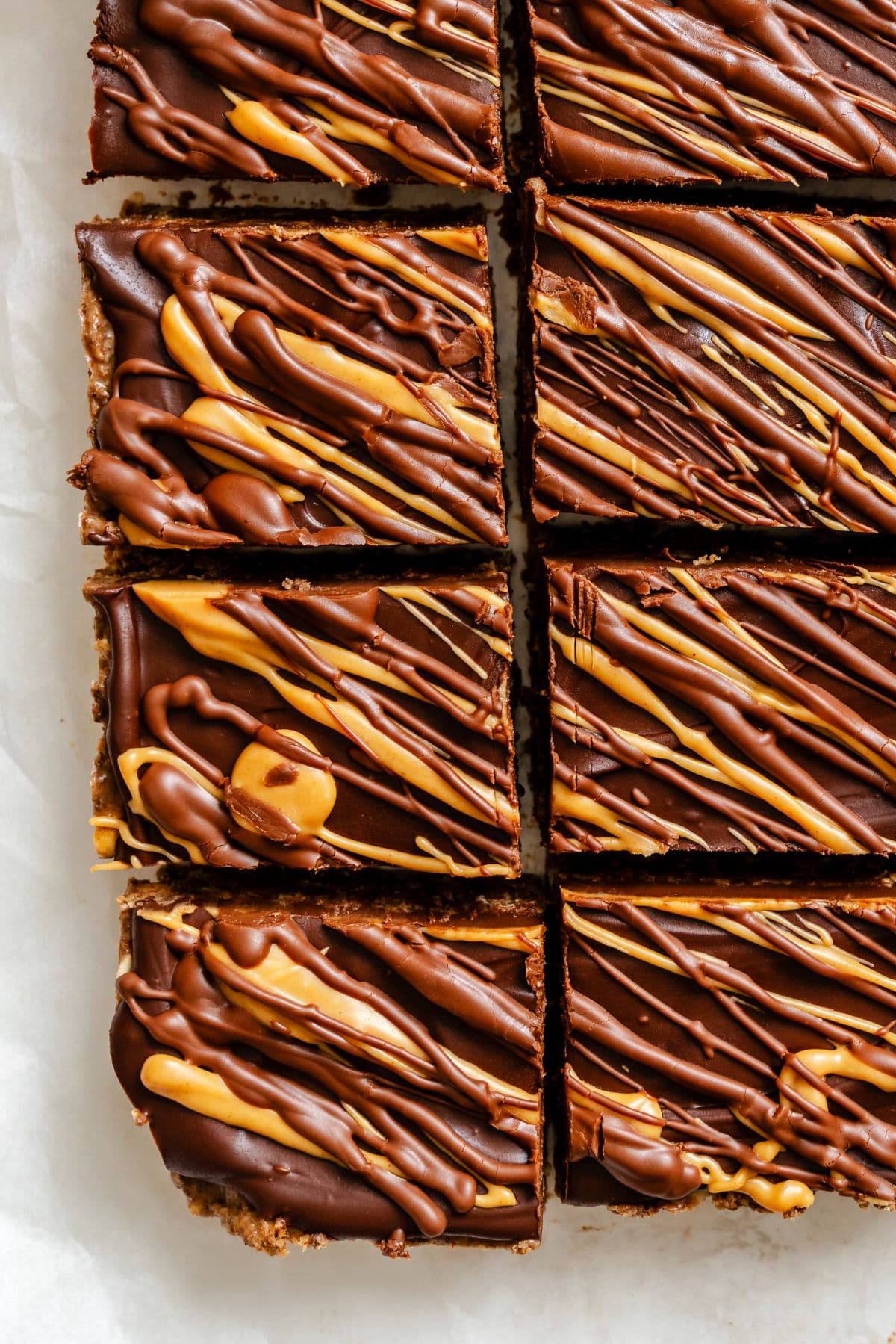 Cut no bake cookie bars in a row on white parchment paper.