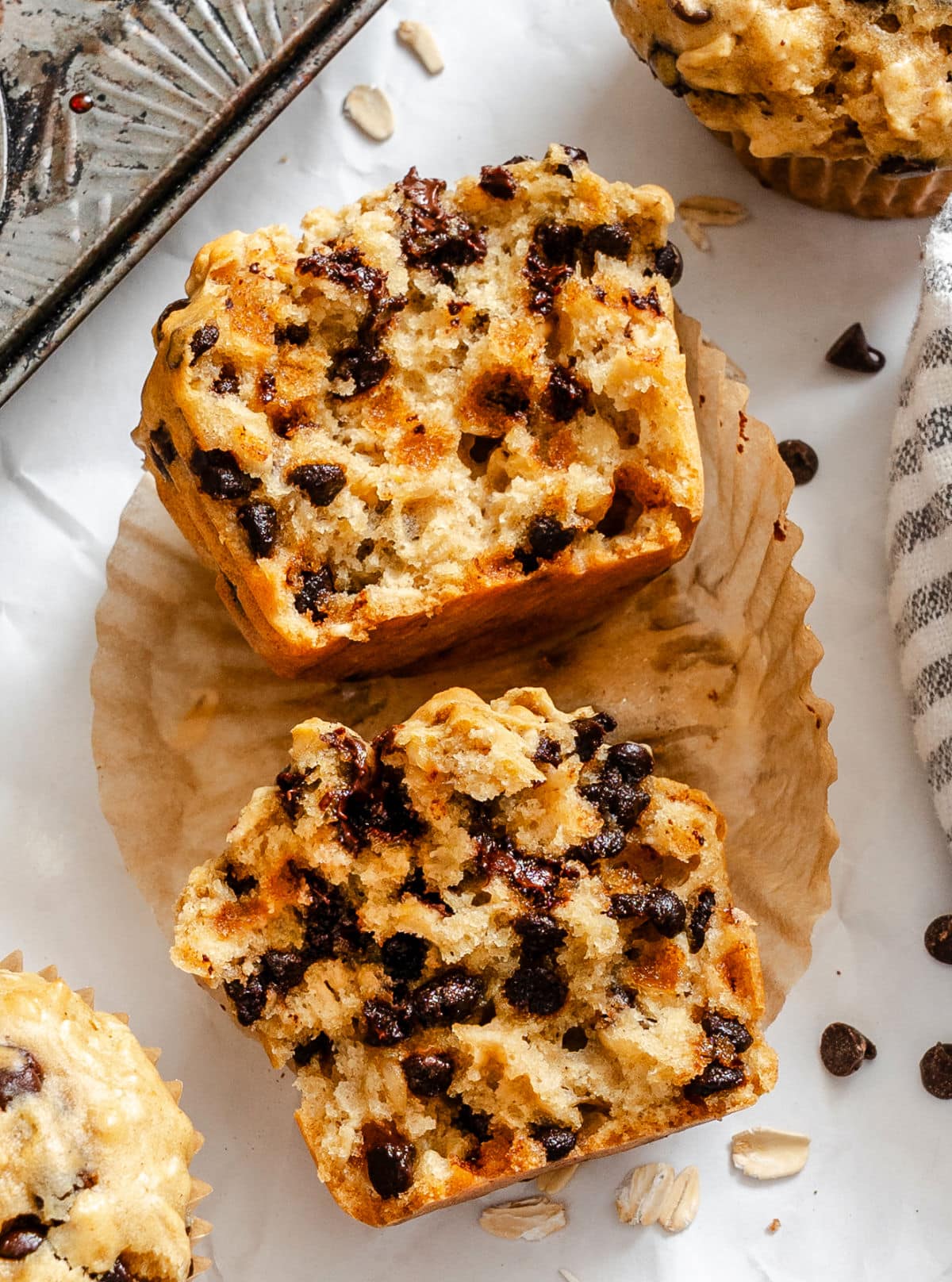 An oatmeal chocolate chip muffin cut in half in a muffin liner. 
