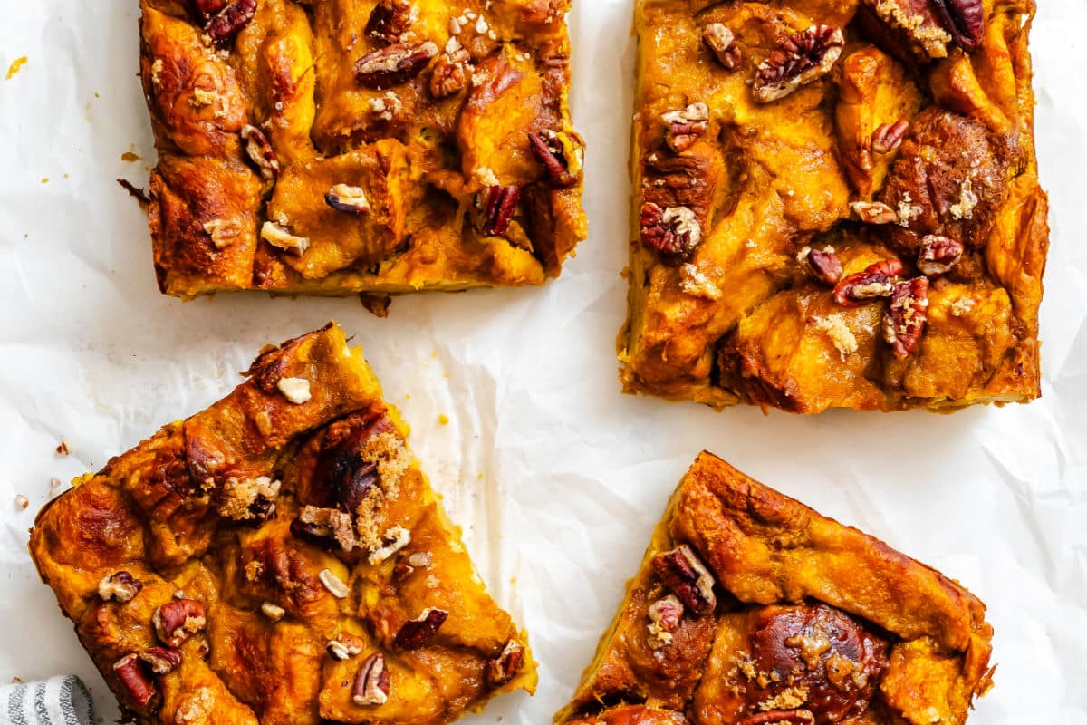 Slices of pumpkin bread pudding on white parchment paper.