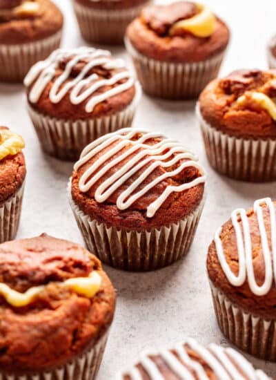 Pumpkin cream cheese muffins drizzled with cream cheese drizzle.
