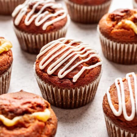 Pumpkin cream cheese muffins drizzled with cream cheese drizzle.