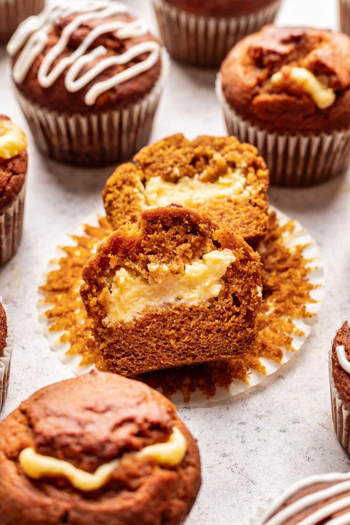 A pumpkin cream cheese muffin cut in half on a paper liner.