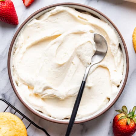 A dish of whipped cream frosting with a spoon in it.