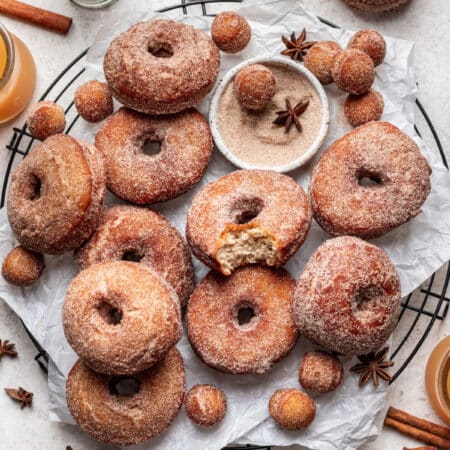 Apple cider donuts on a wire cooling rack with a bite out of the one in the middle.
