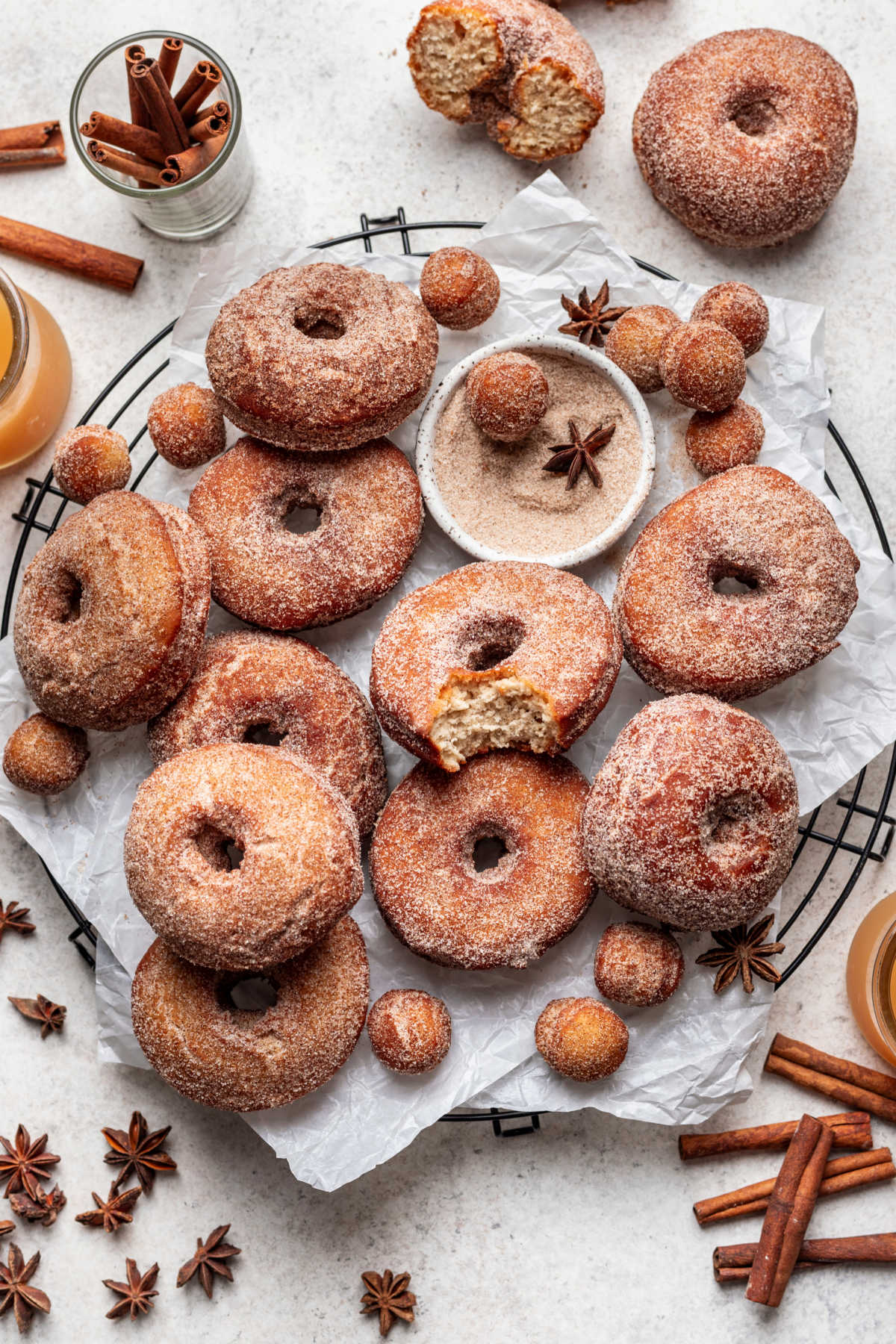 Apple cider donuts on a wire cooling rack with a bite out of the one in the middle. 