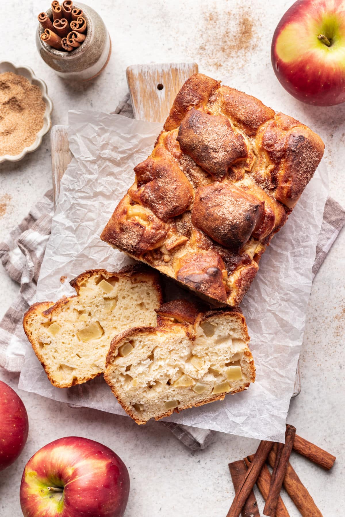 Two slices of apple cinnamon bread leaning next to the loaf.