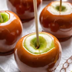 Homemade caramel apples on a sheet of white parchment paper.