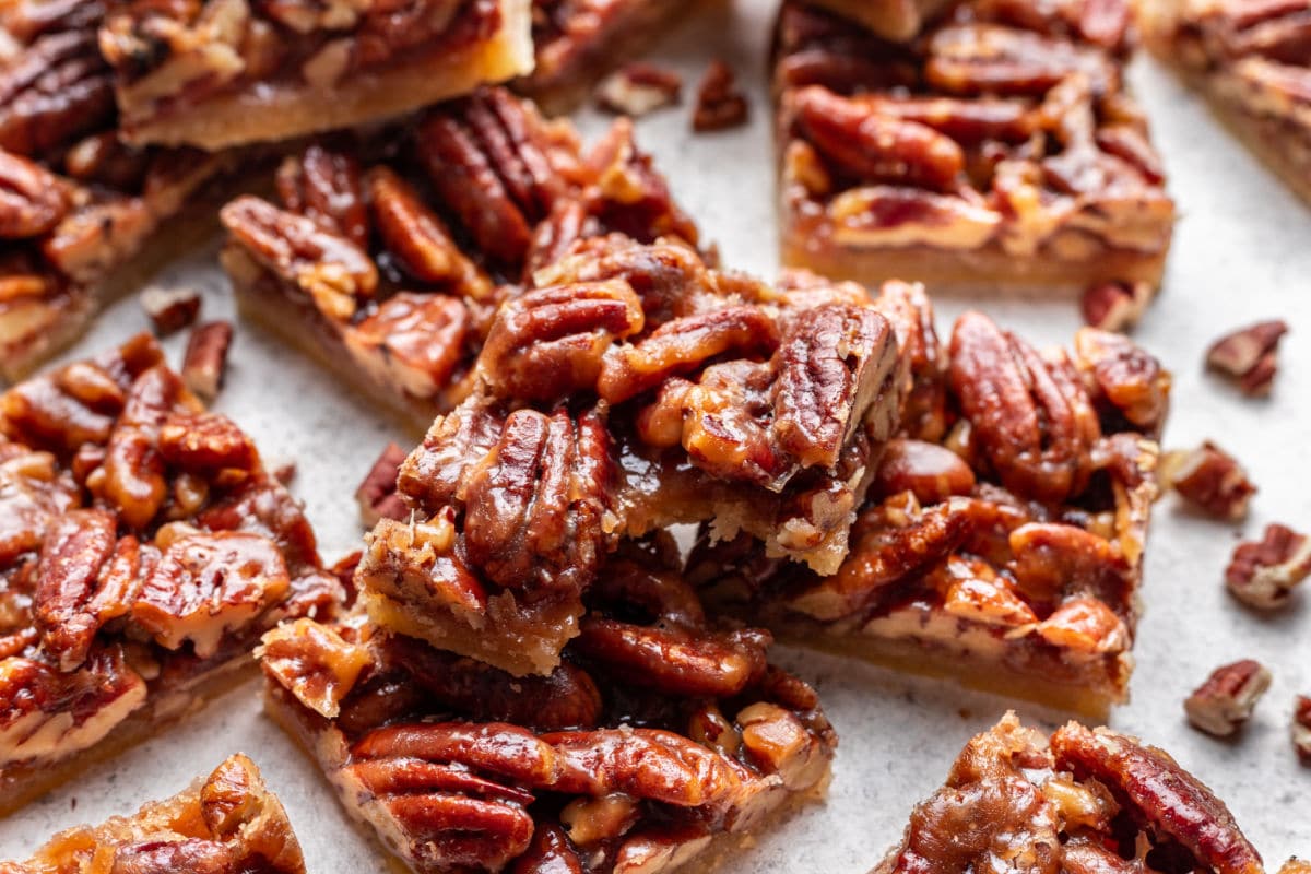 A pecan pie bar with a bite missing on top of other bars. 