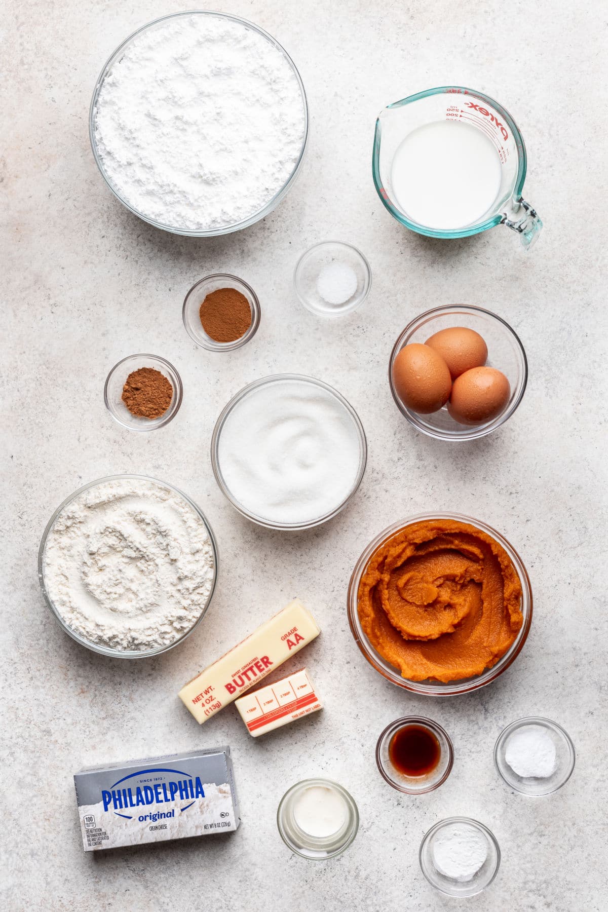 Ingredients for pumpkin cupcakes and cream cheese frosting in dishes.