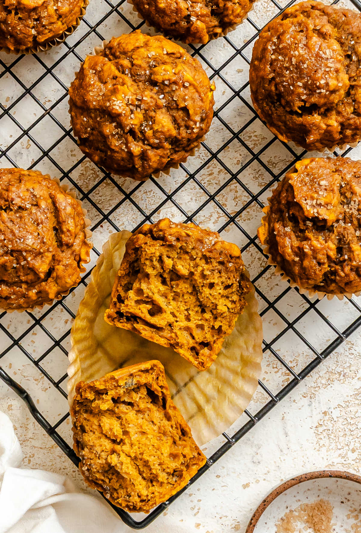 A pumpkin banana muffin cut in half on a wire cooling rack.