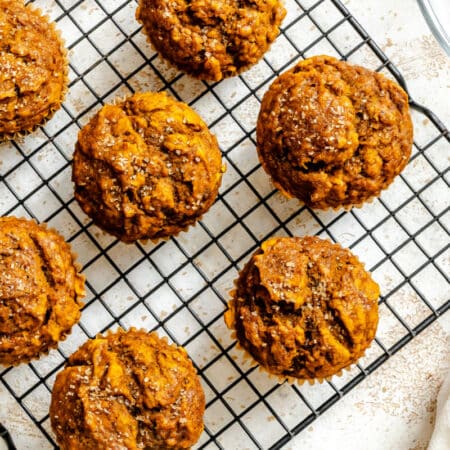 Baked pumpkin banana muffins on a wire cooling rack.