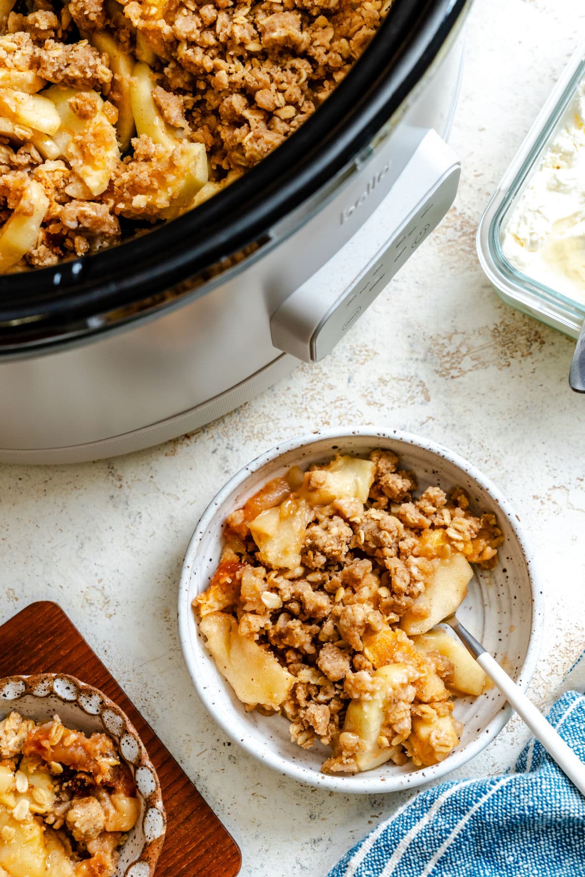 Dishes of slow cooker apple crisp next to the crock pot.