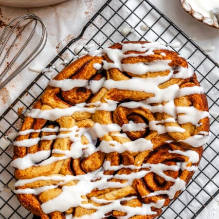 Iced slow cooker cinnamon rolls on a wire cooling rack.