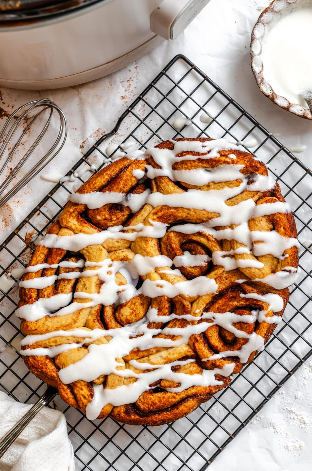 Iced slow cooker cinnamon rolls on a wire cooling rack.