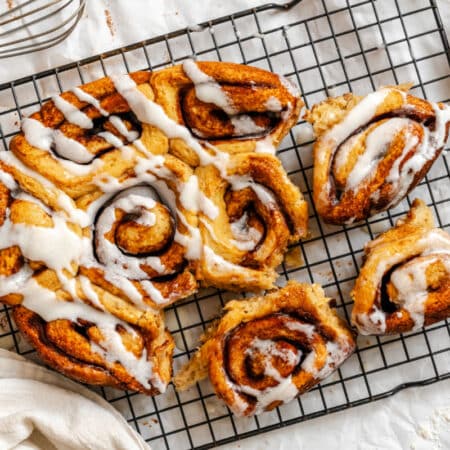 Slow cooker cinnamon rolls on a wire cooling rack with three pulled away.