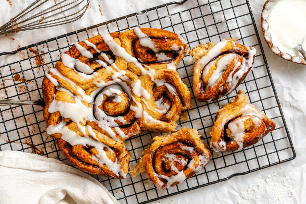 Slow cooker cinnamon rolls on a wire cooling rack with three pulled away.