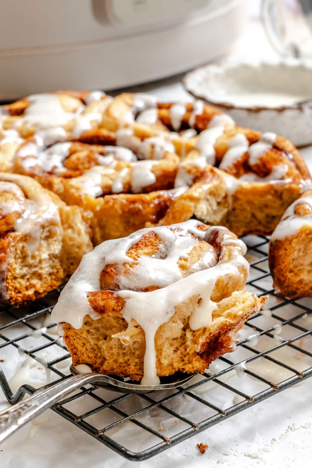 A iced slow cooker cinnamon roll on a server.